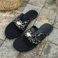 Kryxos leopard print mesh pointed toe flat mules with gold oval hardware, shown on a stone patio.