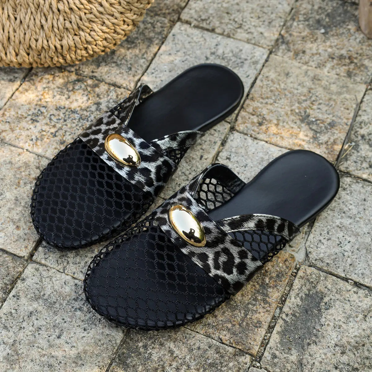 Kryxos leopard print mesh pointed toe flat mules with gold oval hardware, shown on a stone patio.