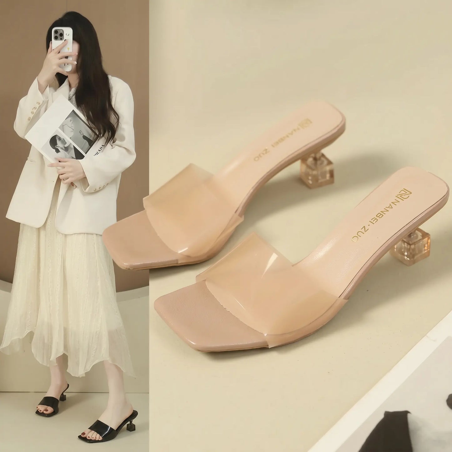 Pair of Kryza nude pink square toe slip-on mule sandals featuring a semi-transparent frosted strap and a clear geometric block heel.