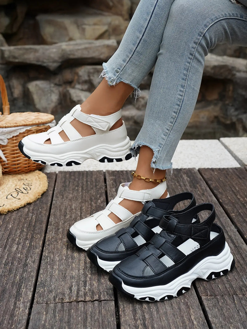 Kryzen white sporty chic chunky platform sandals worn by a model with distressed jeans and a gold anklet, styled outdoors on wooden planks with other shoe variants nearby.