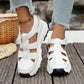 White Kryzen sporty chic chunky platform sandals with open-back cut-out straps worn by a model on a wooden surface, paired with distressed denim jeans.