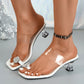 Elegant white slip-on mule sandals featuring a sparkling rhinestone toe strap, clear PVC vamp straps, and a chic clear acrylic block heel worn on a model's feet.