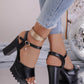 Kylos black PU leather platform high heel sandals styled with distressed denim jeans, featuring a chunky block heel, wavy sole edge, fish-mouth peep-toe, and ankle strap with a charm. Shown on a reflective surface with a disco ball.