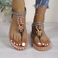 Bohemian flat thong sandals for women featuring intricate beadwork, floral embellishments, and tribal woven straps on a light grey wooden floor.