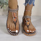 Women's Kylos bohemian flat thong sandals in Rich Earth Brown, featuring intricate beaded floral embellishments and woven patterned straps, worn with denim.