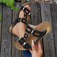 Kyorin black platform wedge sandals with geometric gold embellishments and white stitching shown on a woman's foot with a pearl anklet on a wooden deck.