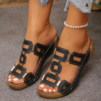 Black Kyorin platform wedge sandals with geometric gold-tone embellishments and white stitching, worn on a model's feet with denim shorts and a pearl anklet.