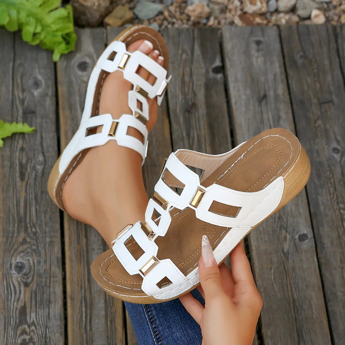 Lifestyle image showcasing Kyorin white platform wedge sandals with gold geometric embellishments on a textured wooden surface, highlighting the comfortable cushioned footbed and stylish T-strap design.