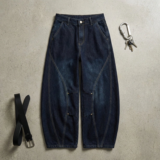 Kyro architectural curved leg jeans in midnight indigo, flat lay view showing the balloon fit, articulated knee darts, and heavyweight denim texture.