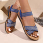 Blue embellished flat sandals with shimmering crossover straps worn on a woman's feet, showcasing their bohemian charm and comfort for summer wear.