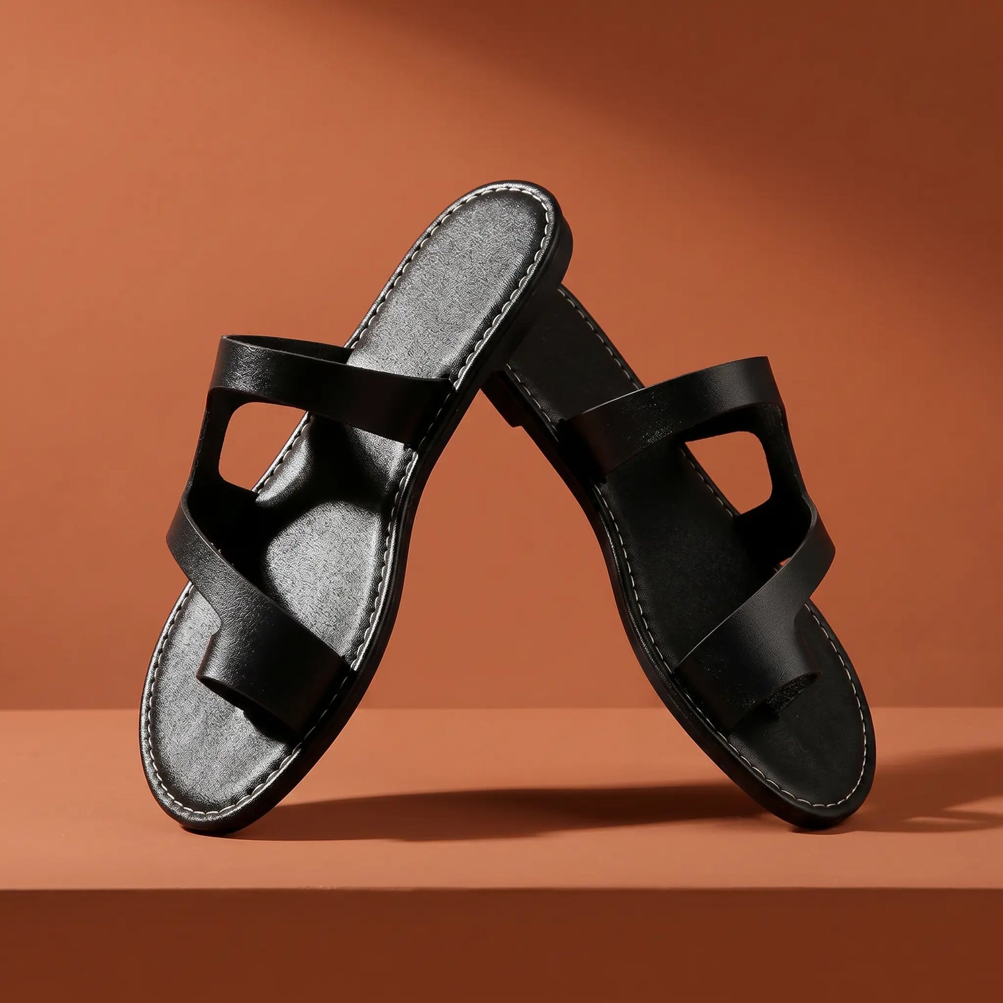 Kyzmiv women's black flat slide sandals featuring an open-toe design and asymmetrical faux leather straps with white sole stitching. These slip-on sandals offer bohemian-inspired elegance for casual wear.