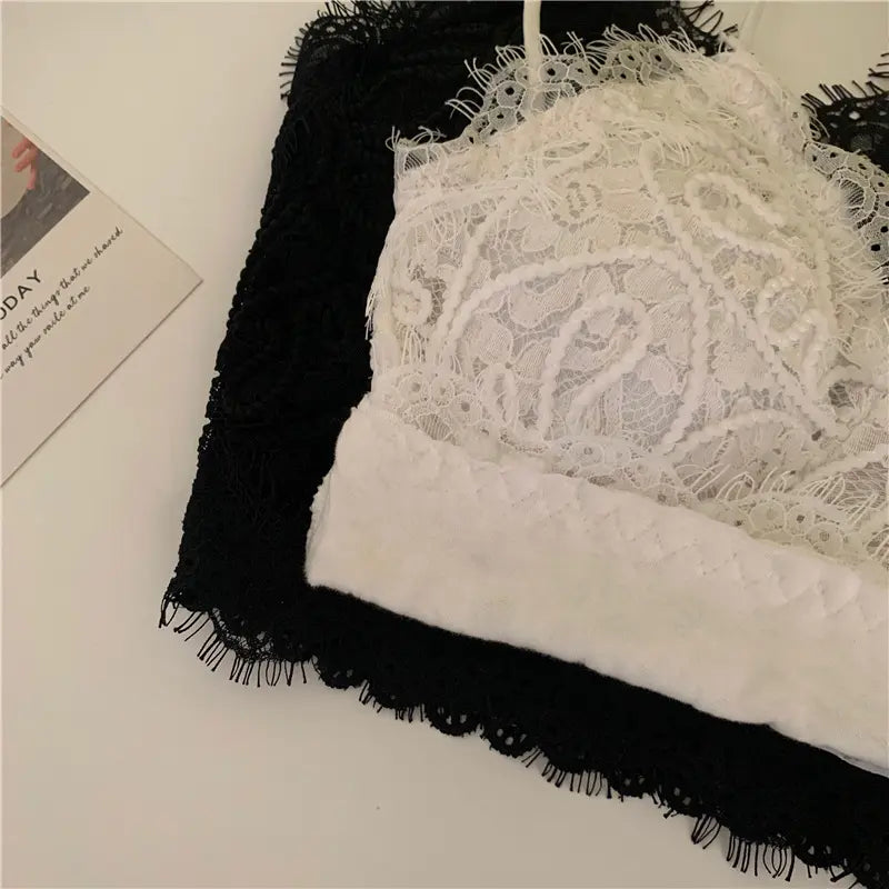 Close-up of Zyrin's romantic white and black cropped lace camisoles, showcasing the intricate floral lace overlay and delicate eyelash trim details.
