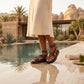 Leopard print vegan leather platform sandals, featuring cross-straps and an antique brass buckle, worn by a model poolside.