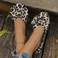 Women's leopard print ballet flats with oversized layered bows, shown from a top-down view on feet wearing an anklet and denim.