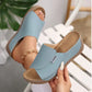 Light blue comfortable platform slide sandals with an open toe and a single wide strap, shown on a foot and being held, featuring a textured wedge sole and contrast stitching.