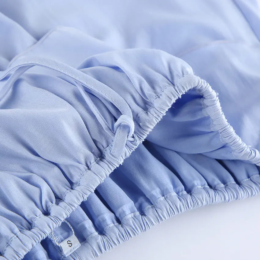 Close-up of the light blue cotton blend fabric featuring an elasticated drawstring waistband and delicate ruffle trim, showcasing premium material quality and craftsmanship.