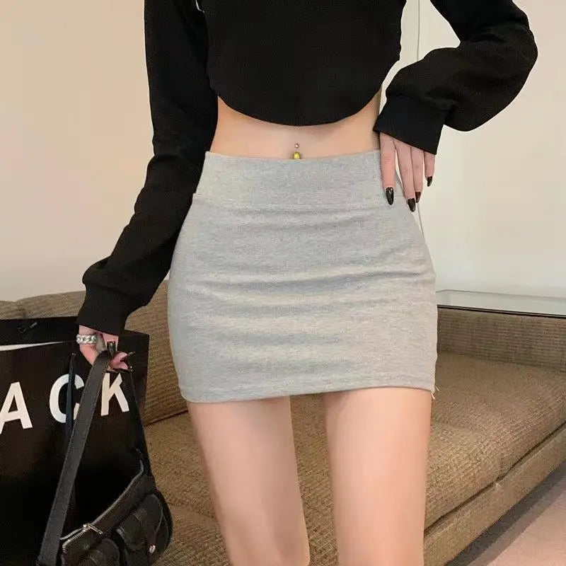 Front view of a model wearing a light gray high-waisted bodycon mini skirt, highlighting its smooth knit and form-fitting silhouette.