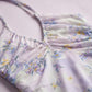 Close-up of the Zevrak Romantic Floral Mesh Ruched Maxi Dress, showcasing the delicate lilac mesh fabric with a watercolor floral print in yellow and blue, and the intricate horizontal ruching on the bodice.
