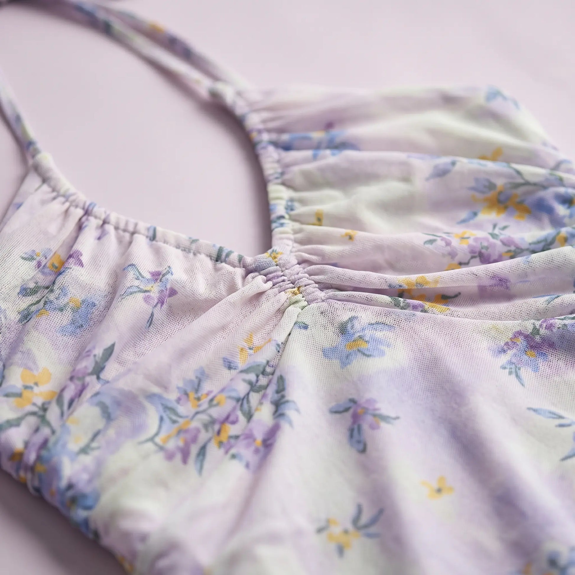 Close-up of the Zevrak Romantic Floral Mesh Ruched Maxi Dress, showcasing the delicate lilac mesh fabric with a watercolor floral print in yellow and blue, and the intricate horizontal ruching on the bodice.