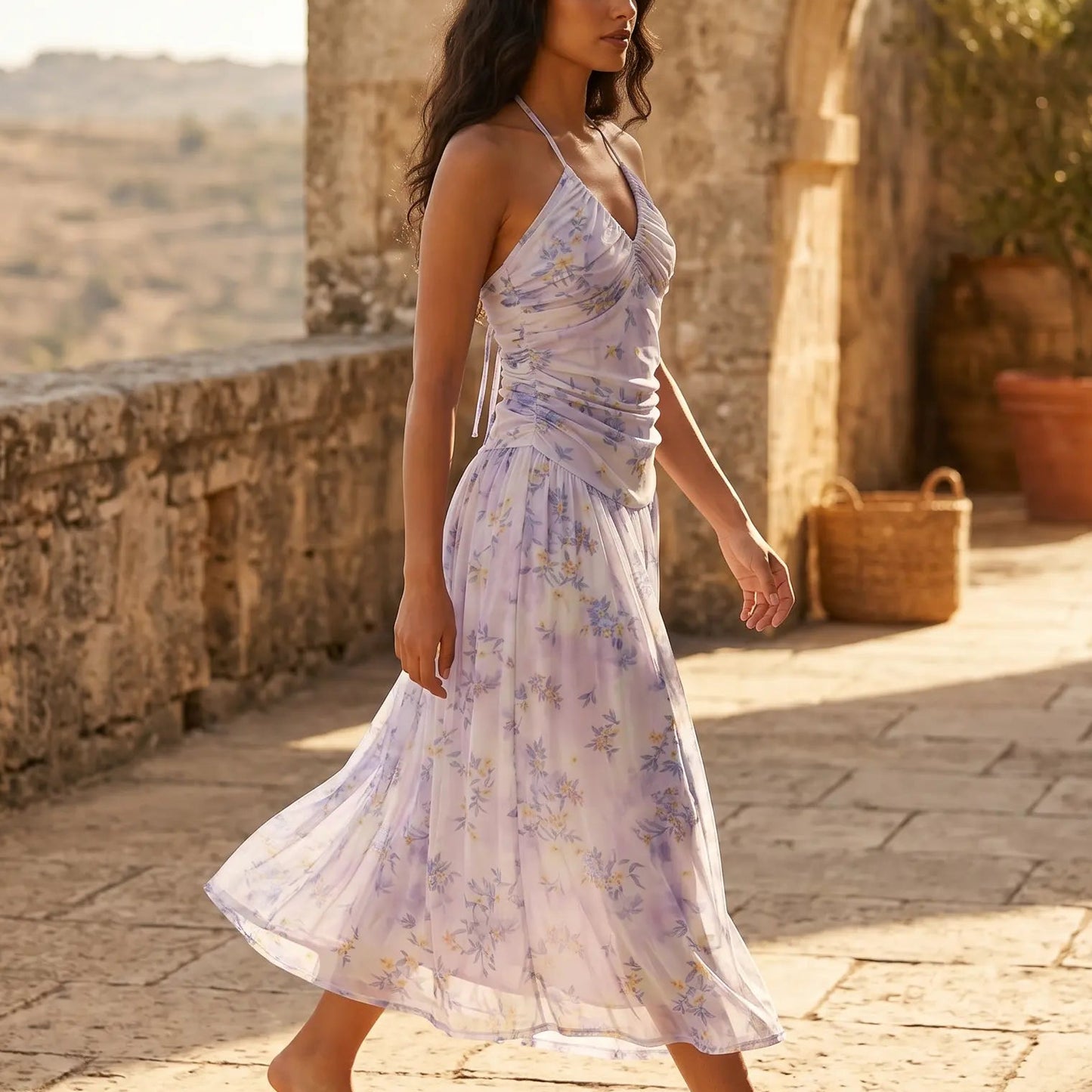 Model walking in a Zevrak lilac floral mesh maxi dress, featuring a ruched halter bodice and a flowing A-line skirt in a sunny outdoor setting.