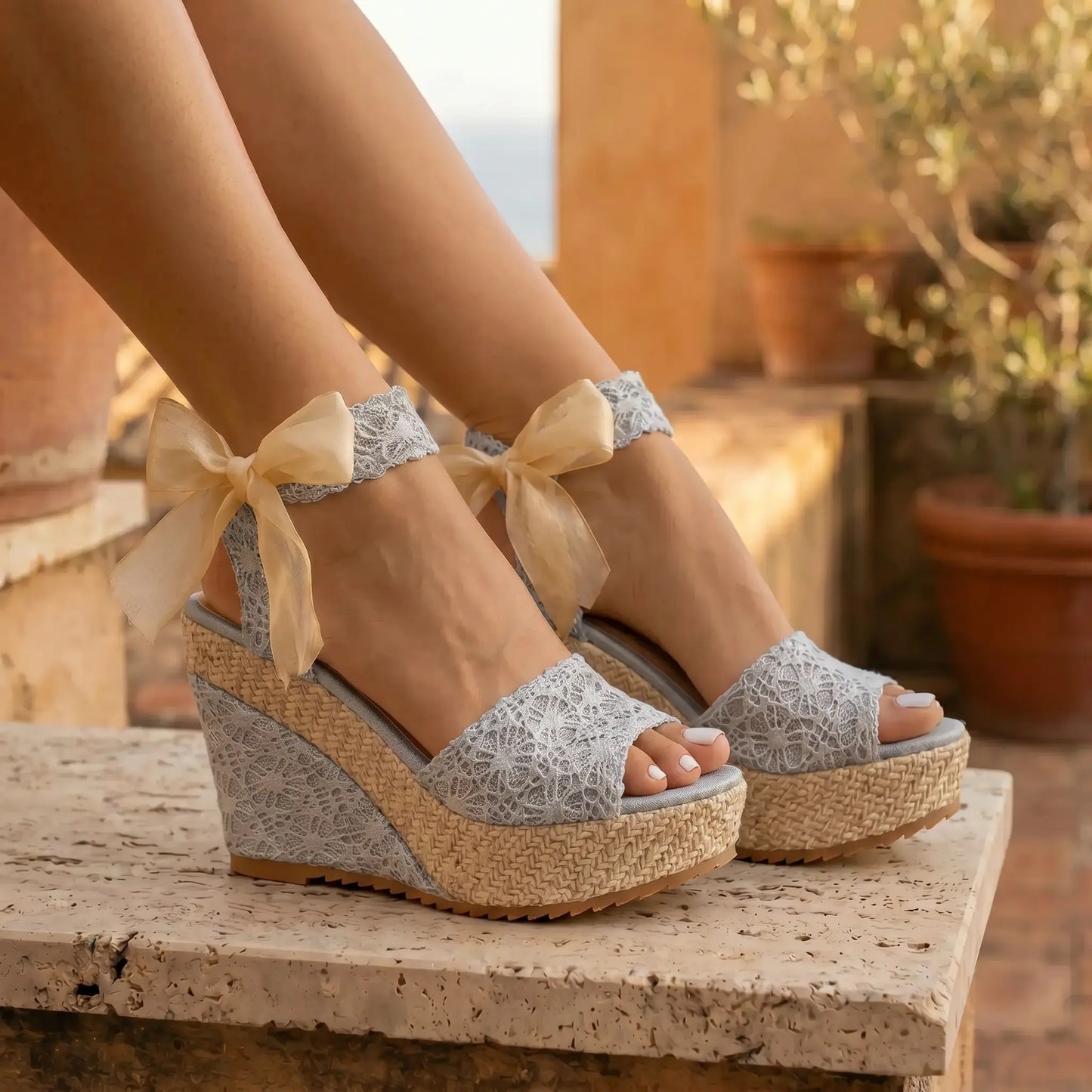 Luminous Silver Lace espadrille platform wedge sandals worn by a model. Features intricate silver lace upper straps, sheer ribbon ankle ties, and a woven espadrille platform in an outdoor setting.