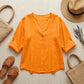 Luvana linen blend blouse in sunset orange with V-neck and half-sleeves, styled in a summer flat-lay with straw accessories.