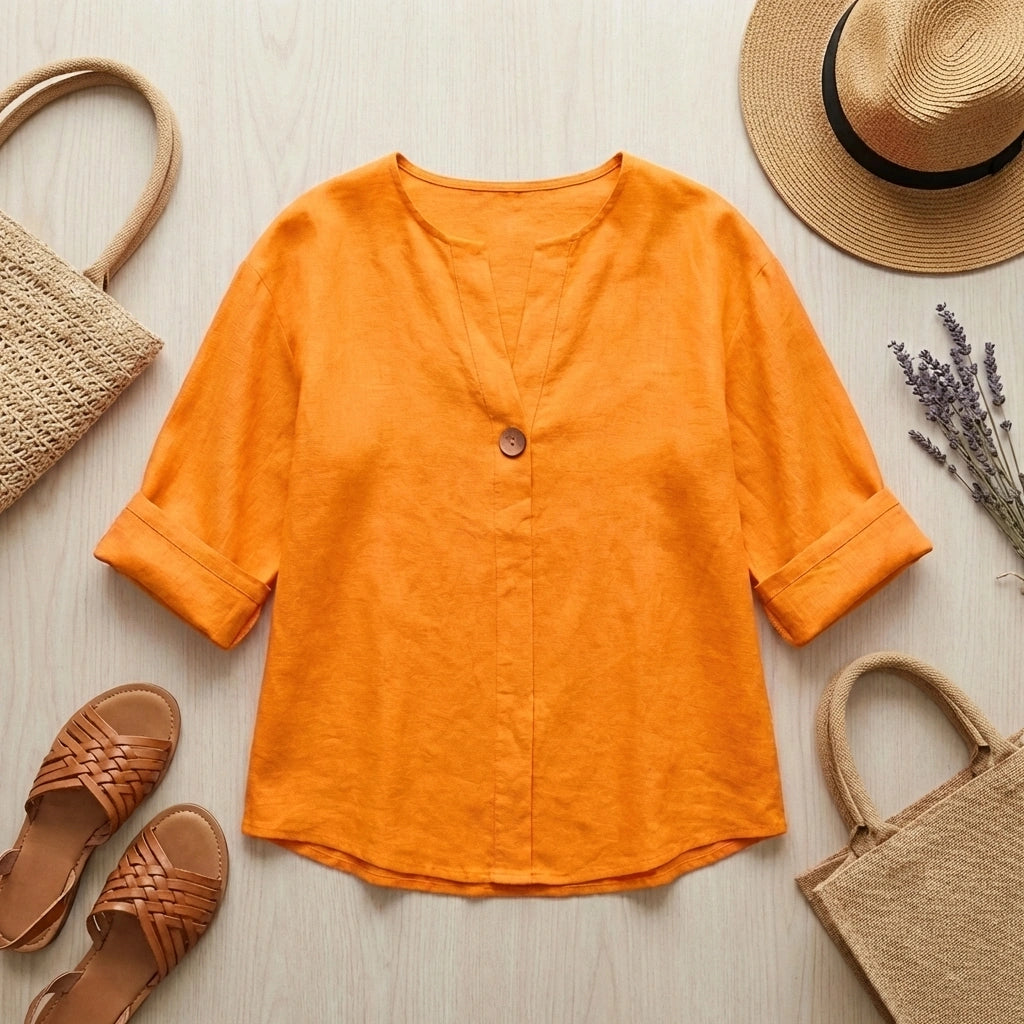 Luvana linen blend blouse in sunset orange with V-neck and half-sleeves, styled in a summer flat-lay with straw accessories.