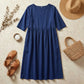 Luvia cotton linen midi dress in deep ocean blue, displayed in a coastal flat-lay with a straw hat and woven sandals.