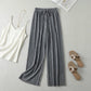 Luvia wide-leg pleated plissé trousers in slate silver, styled in a flat-lay outfit with a white camisole and sandals.