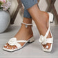 Elegant Luxe Off-White heeled mules with a delicate fabric rose embellishment on the strap, worn by a model with white-painted toenails.