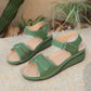 Green Lyraia comfort wedge sandals with peep-toe front and adjustable hook-and-loop straps shown in a natural outdoor setting with sand and plants.