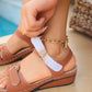 Close-up of a woman's foot wearing tan Lyraia comfort wedge sandals with an ornate gold anklet, showcasing the peep-toe design and adjustable strap.