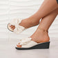 Creamy white Lysa wedge slide sandals featuring a large, layered bow detail on the single strap, shown worn on feet with a subtle wedge heel and ankle bracelet.