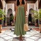 Voluminous Matcha Green Bohemian Maxi Dress with spaghetti straps and gathered neckline, worn by a woman walking through a Moroccan courtyard.