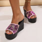 Close-up lifestyle view of sparkling purple sequin wedge slide sandals with a pink trim, worn on a female model's feet against a clean studio background. The sandals feature an 8cm wedge heel and a 3-4cm platform.