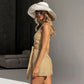 Model wearing a Mavrix oatmeal beige belted wide-leg romper with square neckline and tank straps, styled with a wide-brim hat and sunglasses in a studio setting.
