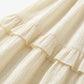 Close-up of the Zyrak creamy pale yellow Romantic Textured Ruffle Maxi Dress fabric, highlighting the micro-crinkle woven grid and soft ruffled seam detail.