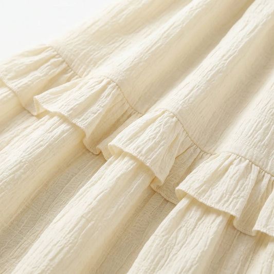 Close-up of the Zyrak creamy pale yellow Romantic Textured Ruffle Maxi Dress fabric, highlighting the micro-crinkle woven grid and soft ruffled seam detail.