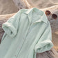 Close-up of the elegant Mint Breeze linen-blend maxi shirt dress laid flat on a weathered log, showcasing its classic collar, pearl-toned buttons, and natural fabric texture.
