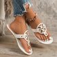White Miraya embellished flat thong sandals with ornate circular cut-out vamp and gold stud accents, shown on a woman's feet with ripped jeans.