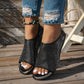 Miroka women's black perforated PU leather flat sandals with a peep-toe and single strap, worn with distressed jeans and a turquoise anklet on a wooden deck.