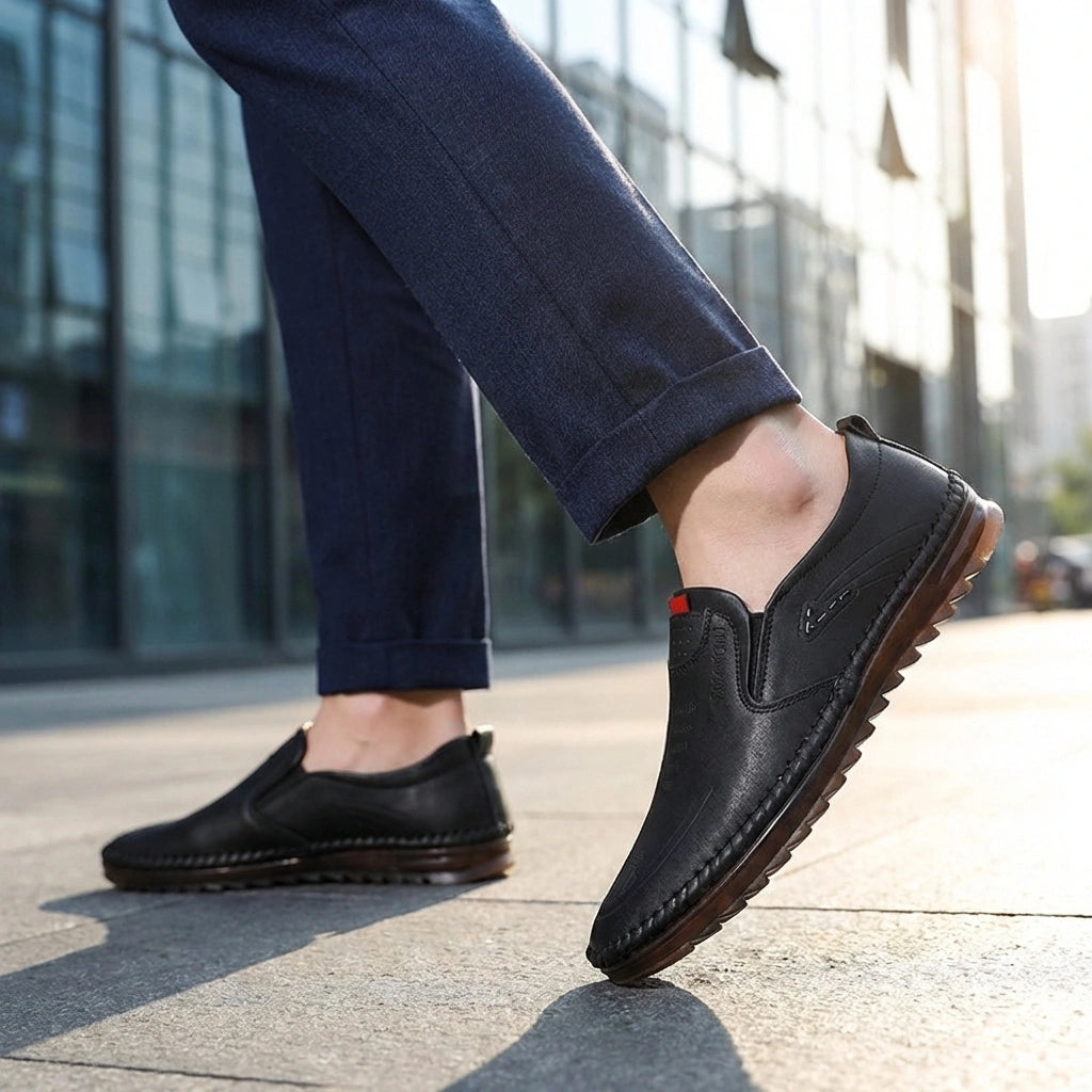 Mokasso men's comfort driving loafer in black vegan leather worn outdoors, showing the flexible rubber sole bending naturally as the model steps.