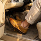 Mokasso men's comfort driving loafer in saddle brown vegan leather shown pressing a car pedal inside a vintage vehicle.