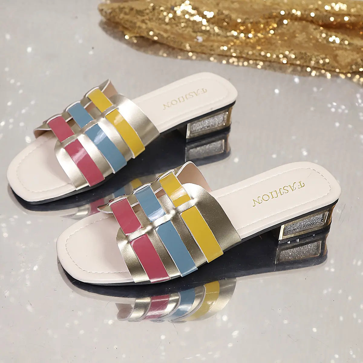 Multi-color woven block heel slide sandals featuring metallic gold, pink, blue, and yellow straps, with a glitter heel accent and square toe.