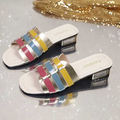 Multi-color woven block heel slide sandals featuring metallic gold, pink, blue, and yellow straps, with a glitter heel accent and square toe.