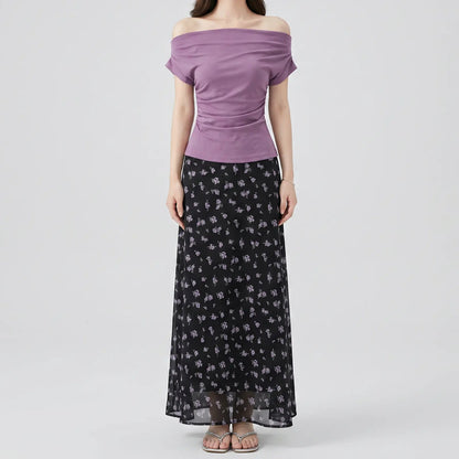 Model wearing Myrven's off-shoulder dusty mauve top with draped ruching and a black maxi skirt with delicate lavender floral print.