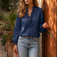 Woman wearing a Zokiru navy blue ruffled V-neck blouse with long sleeves and light wash jeans, standing by a carved wooden door.
