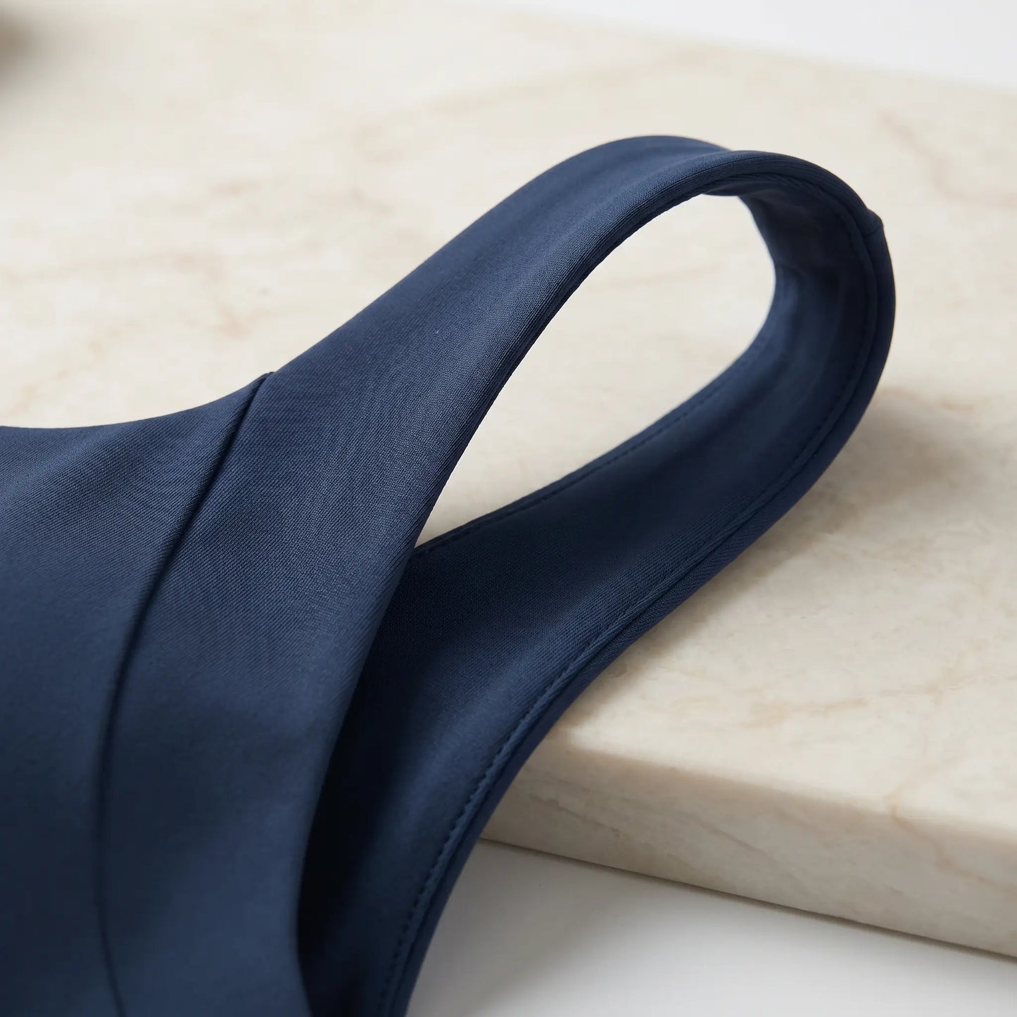 Close-up of the smooth, matte navy blue performance fabric of the Zykari V-Back Yoga Sports Bra's wide shoulder strap, showcasing its fine stitching.