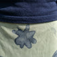Close-up detail of the deep navy knit fabric from the V-neck top and the pale sage green mesh overlay of the maxi skirt with dark abstract patterns.