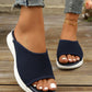 Navy blue breathable knit slide sandals worn by a woman with white-painted toenails, showcasing the slip-on design and contoured footbed on a wooden deck.